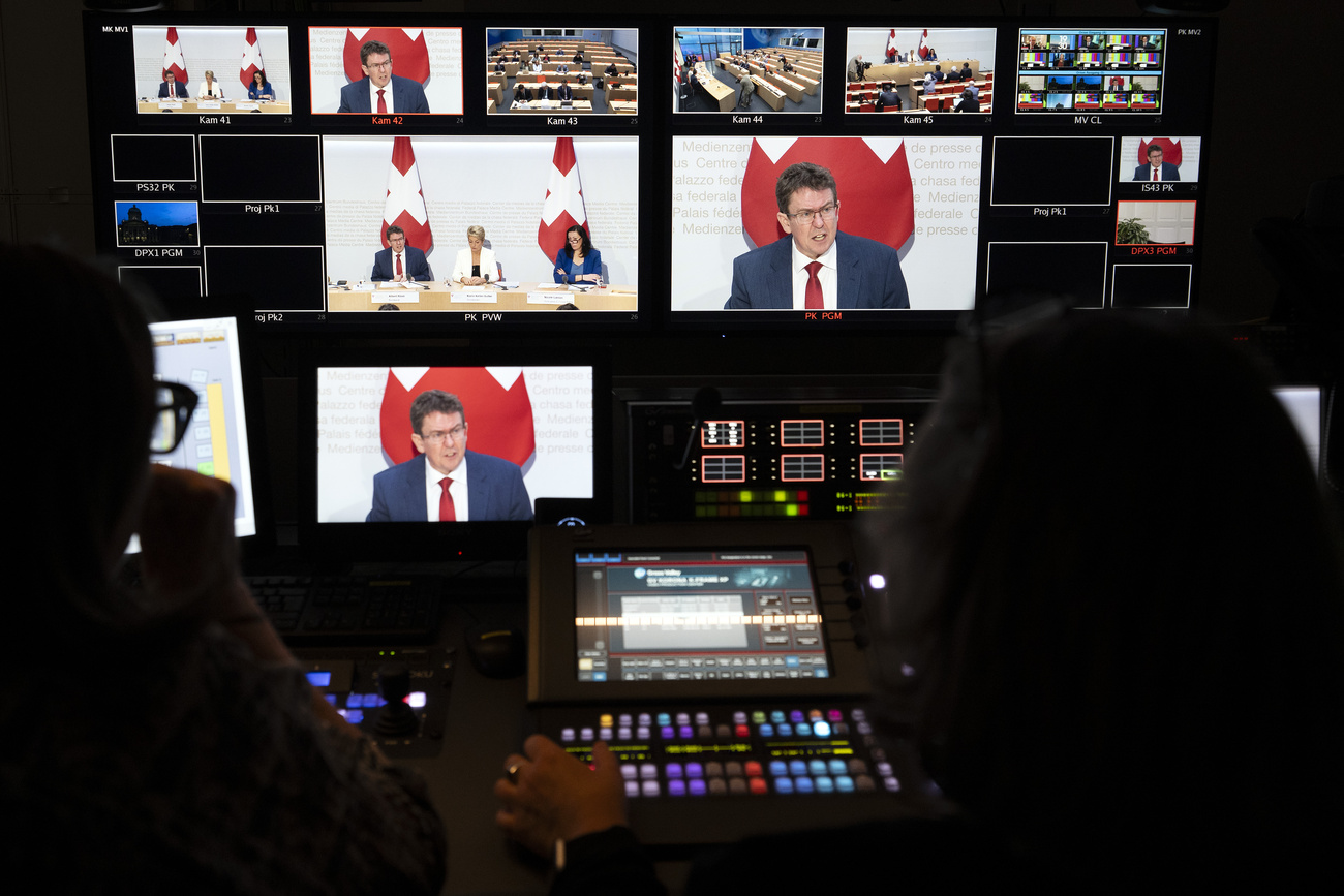 TV control room with several screens showing Federal Councillor Albert Rösti at a media conference.